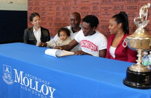 Jared Lovelace '15 signs with Wisconsin as his family watches. Kawan Lovelace '94 to Jared's right.